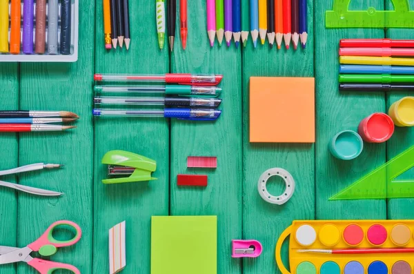 Creative school concept. Arranged school accessories on a green desk.