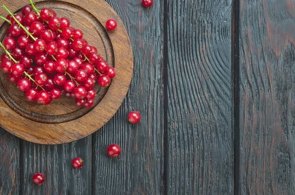 Red fruit in the kitchen. Red currant on a brown wooden table.