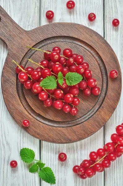 Red fruit in the kitchen. Red currant on a white wooden table.