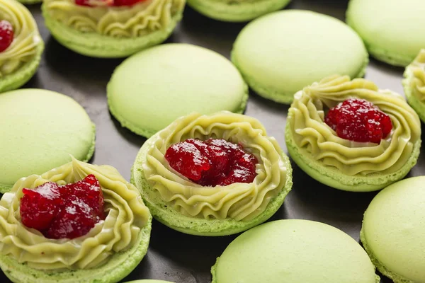 Green macaroons with pistachios ganache cream and raspberries co — Stock Photo, Image