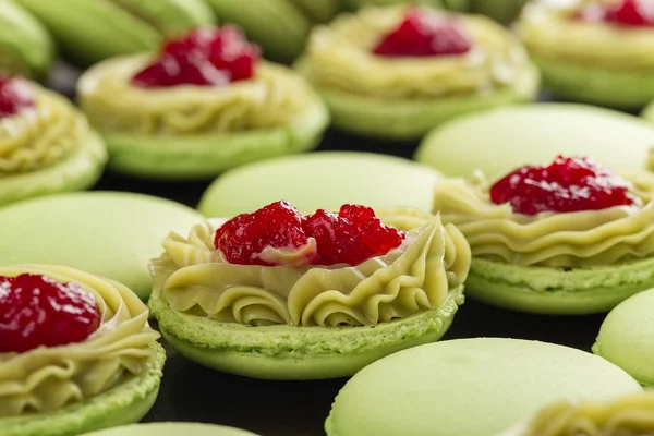 Green macaroons with pistachios ganache cream and raspberries co — Stock Photo, Image