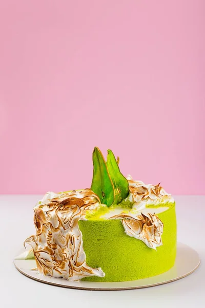 Green cake decorated with burned meringue and colored pear slice — Stock Photo, Image