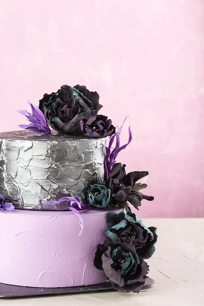 Torta nuziale a più livelli con fiori falsi neri su sfondo rosa — Foto Stock