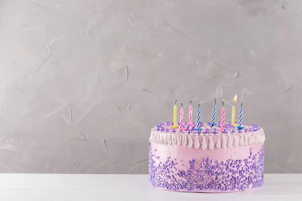 Bolo de aniversário rosa com velas coloridas sopradas — Fotografia de Stock