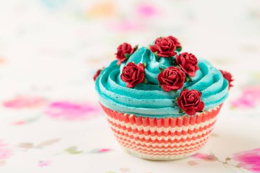 Mavi cupcake sahte kırmızı gül ile dekore edilmiştir.