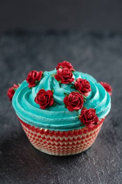Siyah arka plan üzerine sahte kırmızı Güllü mavi cupcake