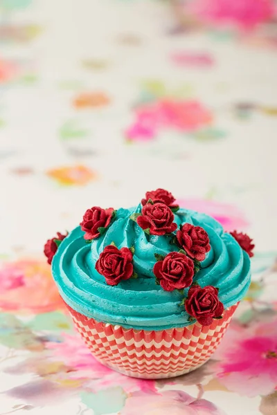 偽の赤い薔薇をあしらった青のカップケーキ — ストック写真