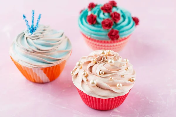 Três cupcakes coloridos no fundo rosa — Fotografia de Stock