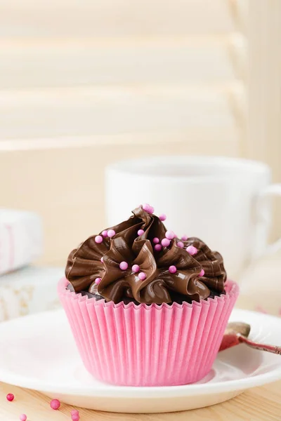 Magdalena de chocolate con espolvoreos en taza rosa — Foto de Stock