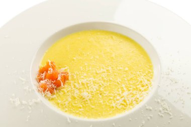 Cheese cream soup with salmon and grated parmesan on white plate clipart