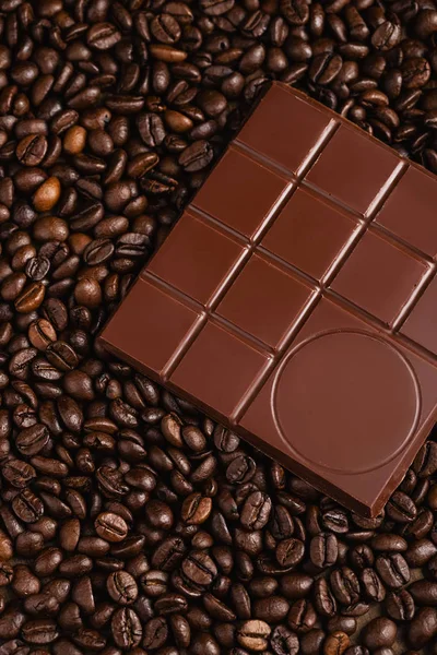 Barra de chocolate amargo sobre fondo de granos de café — Foto de Stock