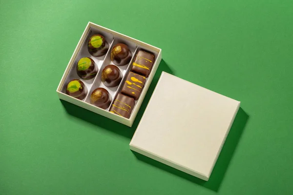 Sortimento de bombons de luxo em caixa sobre fundo verde — Fotografia de Stock