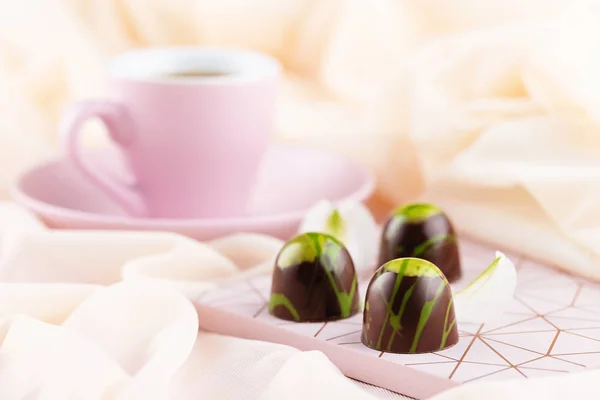 Luxus-Bonbons mit Tasse Kaffee auf pastellrosa Hintergrund — Stockfoto