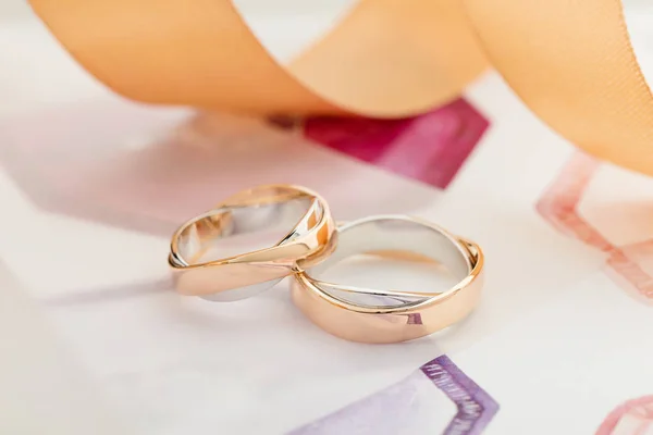 Two white and rose gold wedding rings on pastel background