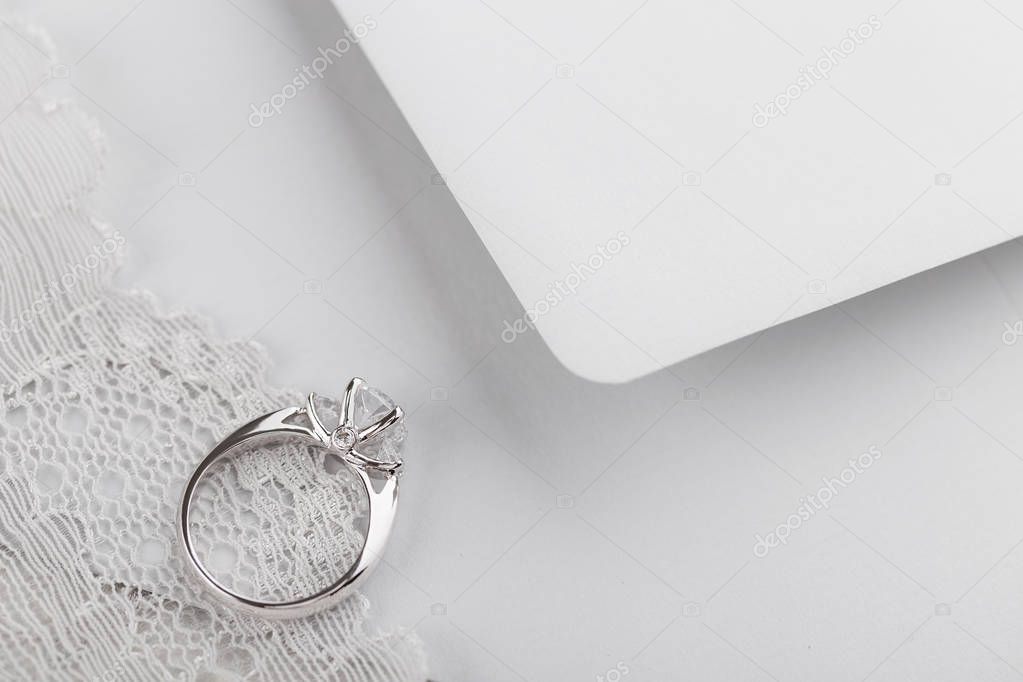 White gold wedding ring with diamonds on gray envelope with copy
