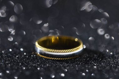 Bokeh siyah zemin üzerine altın ve gümüş yüzük