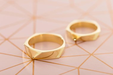 Pastel pembe bir arka plan üzerinde iki altın alyans