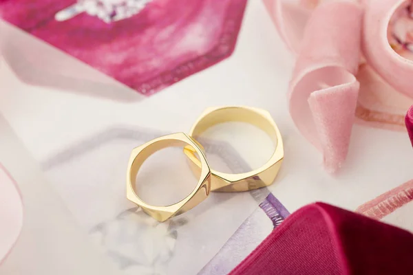 Anillos de boda dorados sobre fondo pastel con cintas rosas —  Fotos de Stock