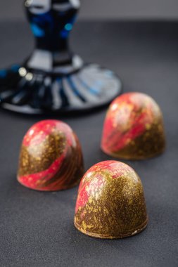 El yapımı çikolata siyah arka plan üzerinde kırmızı ve altın sıçraması ile. E