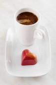 Červené srdce ve tvaru ručně vyráběné čokoládové cukroví na desce s šálkem c