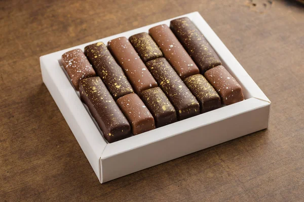 Handgefertigte Bonbons mit Goldspritzern in Schachtel auf Holzgrund — Stockfoto