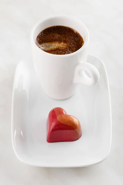 Bonbons au chocolat faits à la main en forme de coeur rouge sur plaque avec tasse de c — Photo