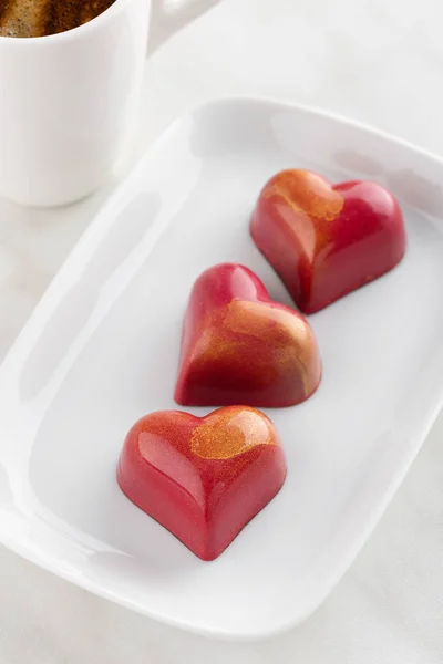 Red heart shaped handmade chocolate candy on plate with cup of c — Stock Photo, Image