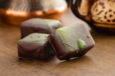 El yapımı bonbon ahşap zemin üzerine yeşil çikolata sıçraması ile dekore edilmiştir. Özel el yapımı çikolata şekerleme. Ürün kavramı için chocolatier