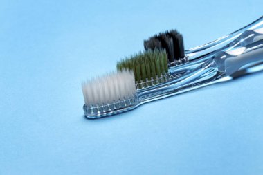 Bulanık mavi arkaplanda diş macunsuz üç diş fırçasını kapat.