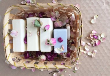 Hasır bir kutuda gül yapraklarıyla kaplı çeşitli şekillerde sabun çubukları. 