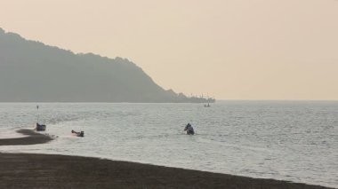 Tekneler ve balıkçılar siluetleri ile puslu tropikal deniz manzarası