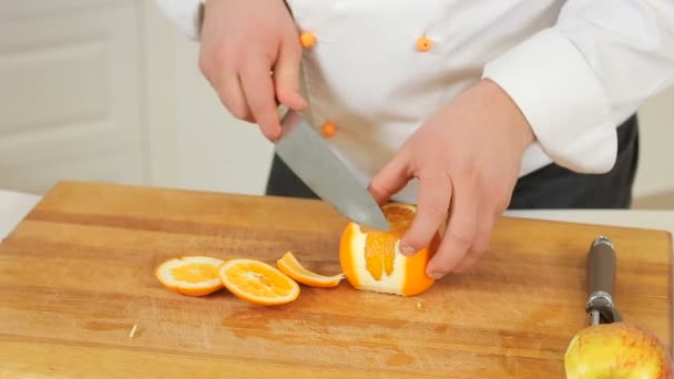 Chef-kok pellen en snijden van een sinaasappel — Stockvideo