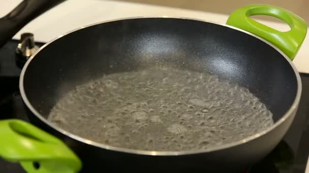 Putting boiling water for cooking in a wok on a stove — Stock Video