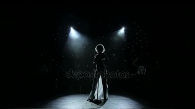 Kadın şarkıcı arkadan aydınlatmalı dumanlı sahnede