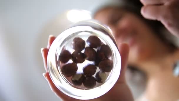 Молода жінка розсіює лісові горіхи у склянці — стокове відео