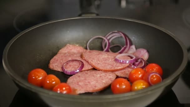 Grelhar tomates cereja frescos salame e fatias de cebola vermelha em uma panela de ato de fritar — Vídeo de Stock