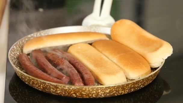 Grelhar salsichas e pão em uma frigideira enquanto cozinha cachorros quentes caseiros — Vídeo de Stock