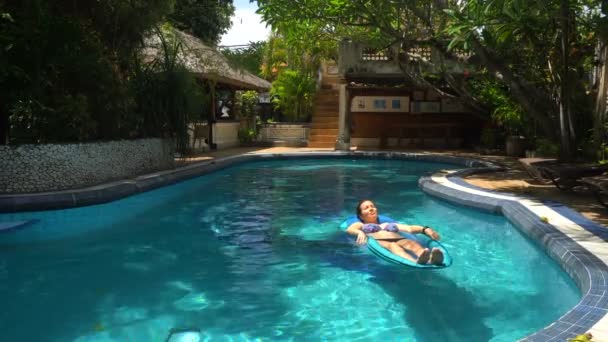 Junge Frau liegt an einem sonnigen Tag auf Wassermatratze im Pool — Stockvideo