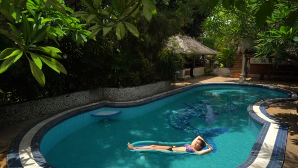 Mladá žena ležící na vodní matraci v bazénu na slunečný den — Stock video