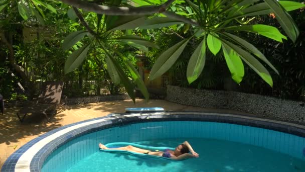 Fiatal nő fekszik a víz matrac a medencében egy napsütéses napon — Stock videók