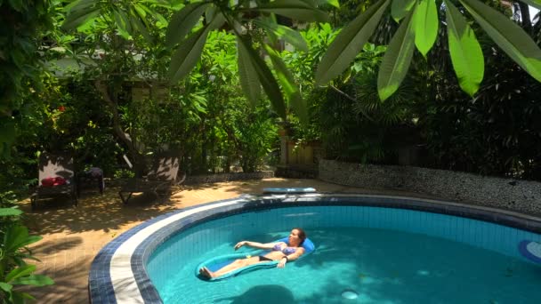 Junge Frau liegt an einem sonnigen Tag auf Wassermatratze im Pool — Stockvideo