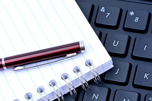 Клавіатура з ручкою і блокнотом — стокове фото
