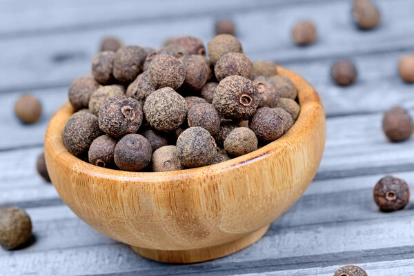 Bamboo bowl with allspice on wooden table