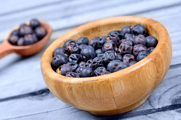 Juniper dalam sendok dan mangkuk di atas meja kayu — Stok Foto