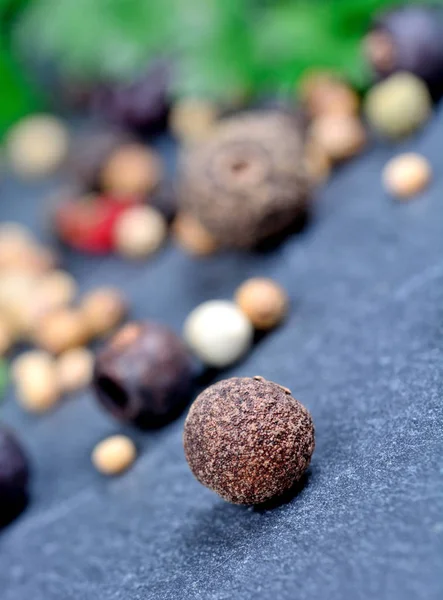 Kryddpeppar, svartpepparkorn, enbär på skiffer — Stockfoto
