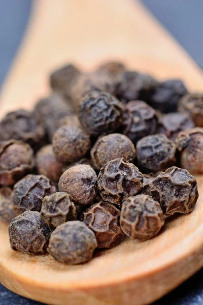 Cuchara de madera con granos de pimienta — Foto de Stock