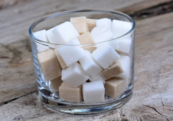 Cubos de azúcar en un vaso sobre la mesa — Foto de Stock