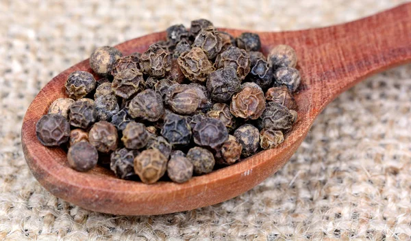 Black peppercorns in a spoon — Stock Photo, Image