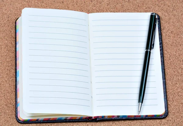 Caderno com caneta sobre fundo de cortiça — Fotografia de Stock