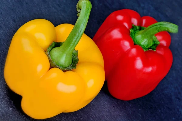 Žlutá a červená paprika na břidlici — Stock fotografie